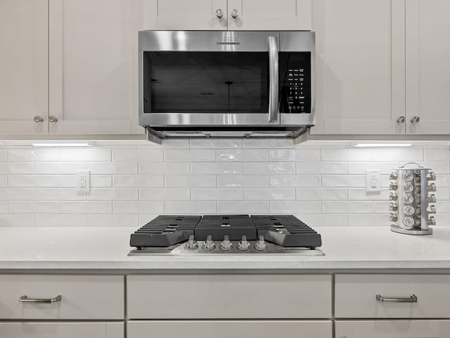 kitchen featuring white cabinetry, stainless steel appliances, light stone counters, and tasteful backsplash