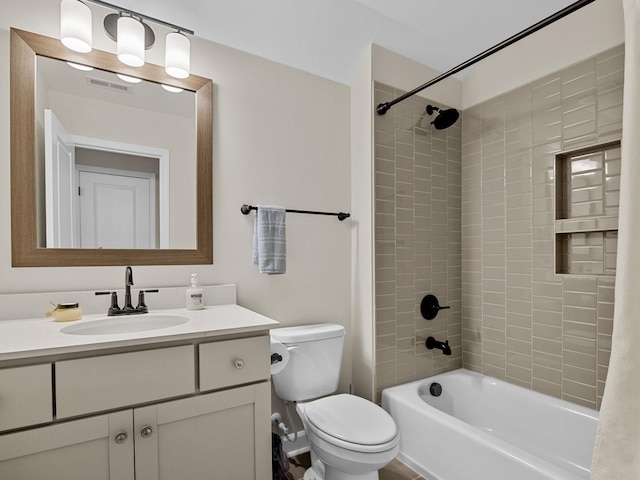 full bathroom with tiled shower / bath, vanity, and toilet