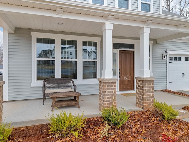 view of exterior entry featuring a porch and a garage