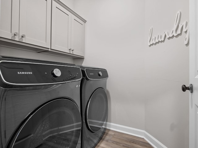 washroom with cabinets, washing machine and dryer, and dark wood-type flooring