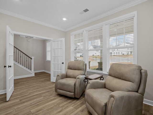 living area with french doors, ornamental molding, and light hardwood / wood-style flooring