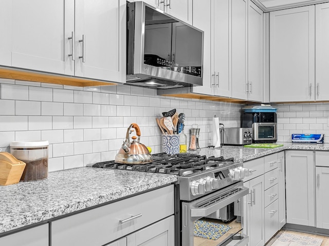 kitchen with tasteful backsplash, stainless steel appliances, and light stone countertops