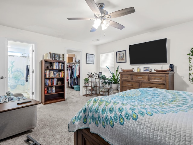 carpeted bedroom with a walk in closet, connected bathroom, ceiling fan, and a closet
