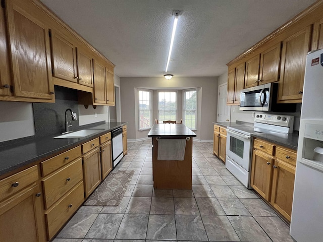 kitchen featuring light tile patterned flooring, a kitchen island, sink, stainless steel appliances, and a textured ceiling