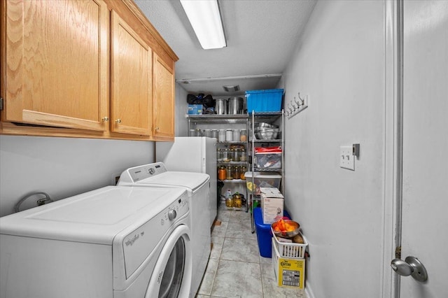 laundry room with light tile patterned floors, cabinets, and washing machine and clothes dryer