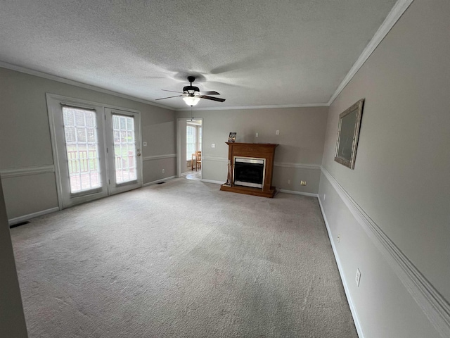 unfurnished living room featuring ceiling fan, ornamental molding, a textured ceiling, and carpet