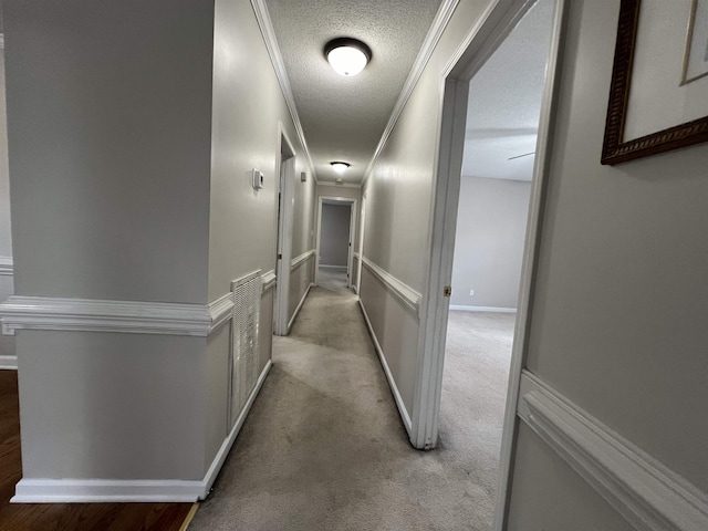 corridor with crown molding, carpet floors, and a textured ceiling