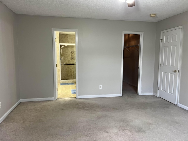 unfurnished bedroom with light carpet, a spacious closet, and a textured ceiling