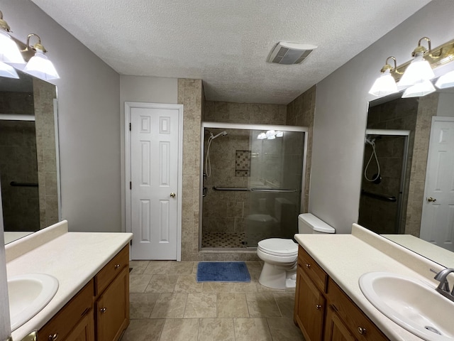 bathroom featuring walk in shower, vanity, toilet, and a textured ceiling