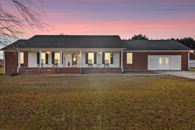 view of front facade with a garage, a lawn, and a porch