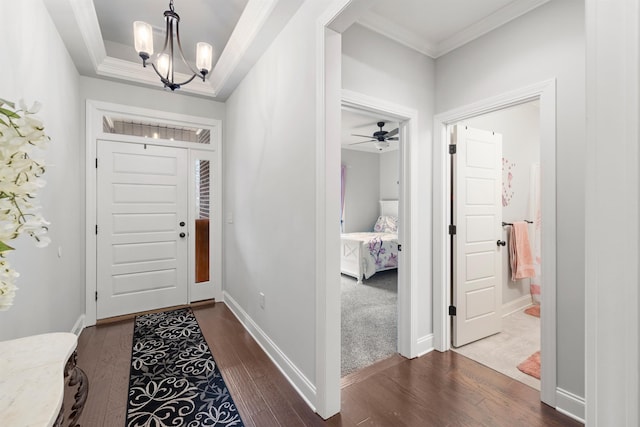 entryway with an inviting chandelier, crown molding, a tray ceiling, and hardwood / wood-style flooring