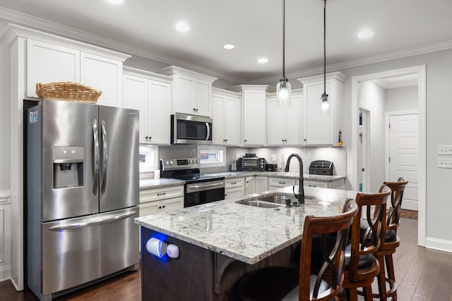 kitchen featuring appliances with stainless steel finishes, decorative light fixtures, sink, a breakfast bar area, and a kitchen island with sink