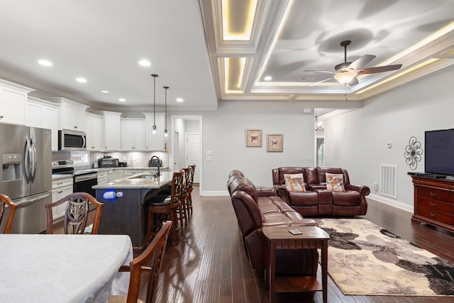 living room with crown molding, dark hardwood / wood-style floors, and sink