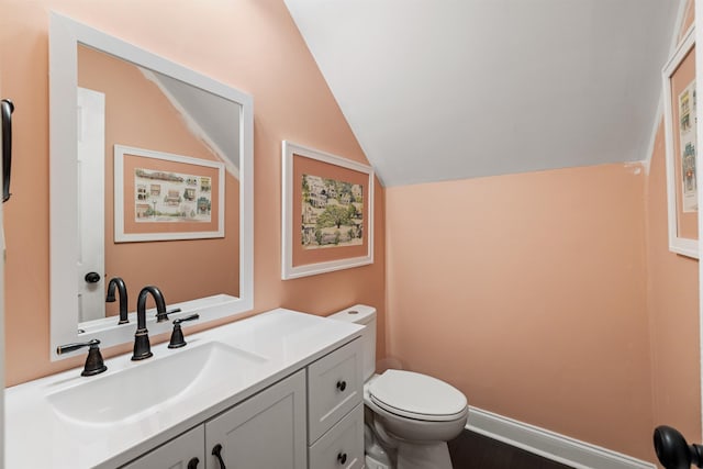 bathroom featuring vanity, vaulted ceiling, and toilet