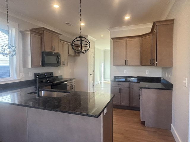 kitchen with pendant lighting, black appliances, sink, dark stone countertops, and kitchen peninsula