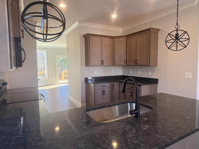 kitchen featuring ornamental molding, sink, pendant lighting, and dark stone counters