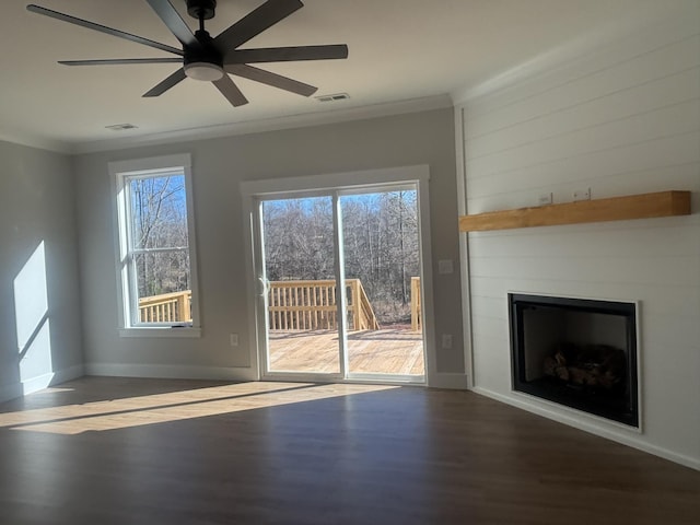 unfurnished living room featuring ornamental molding, dark wood-type flooring, a large fireplace, and ceiling fan