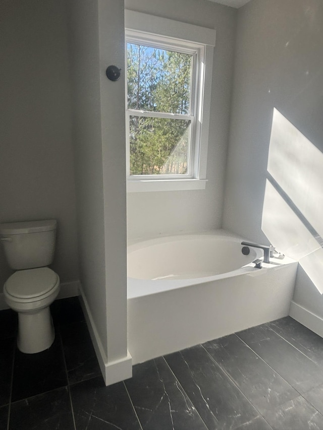 bathroom featuring toilet and a tub to relax in