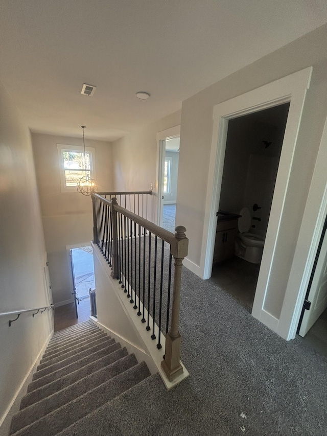 stairway featuring carpet floors and a notable chandelier