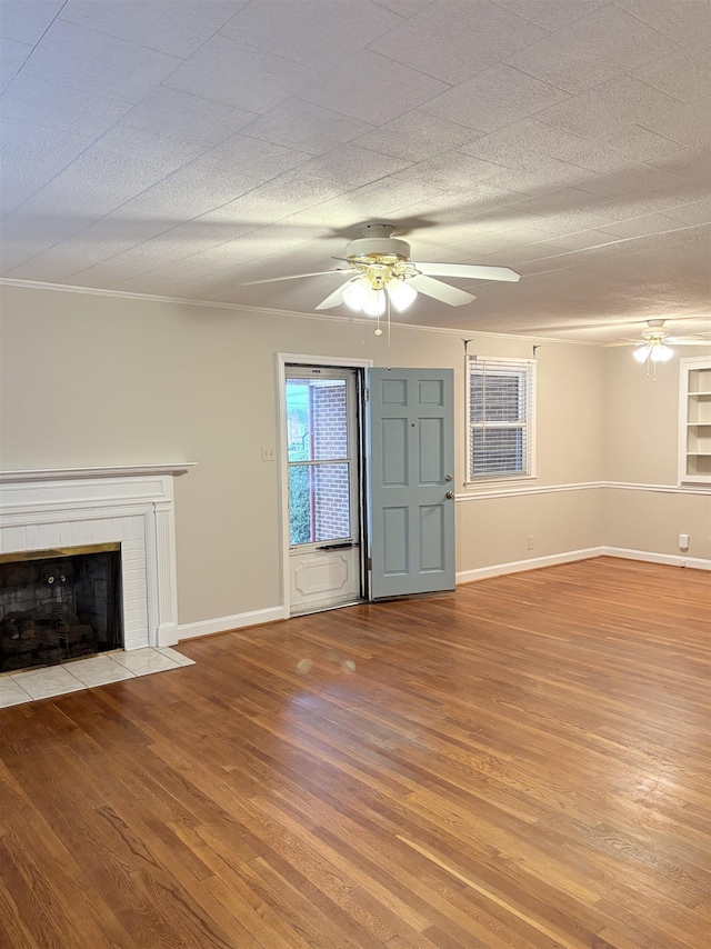 unfurnished living room featuring ceiling fan, ornamental molding, a textured ceiling, and light wood-type flooring