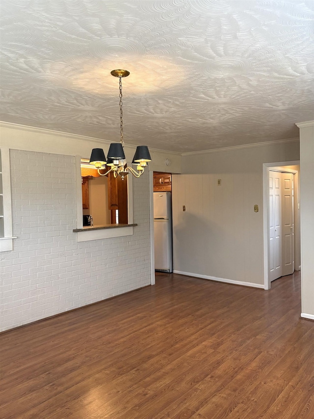 unfurnished living room featuring brick wall, dark hardwood / wood-style floors, an inviting chandelier, crown molding, and a textured ceiling