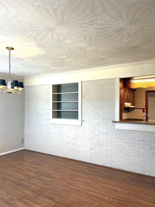 spare room with hardwood / wood-style floors, a notable chandelier, sink, and brick wall