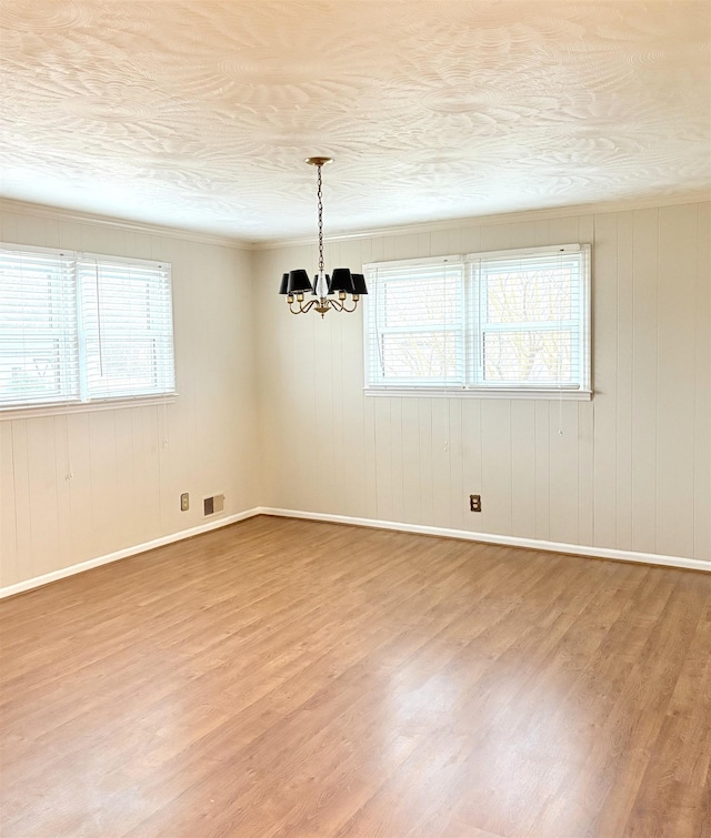 empty room with a notable chandelier, hardwood / wood-style flooring, and a textured ceiling