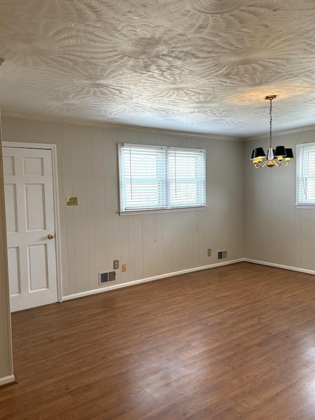 spare room with dark hardwood / wood-style flooring and a chandelier