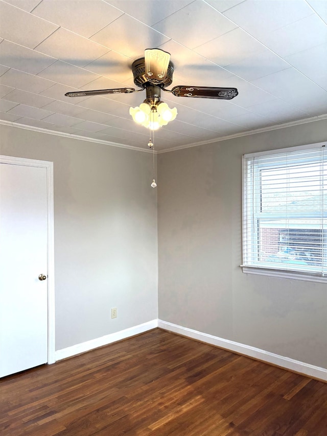 empty room with ornamental molding, dark wood-type flooring, and ceiling fan