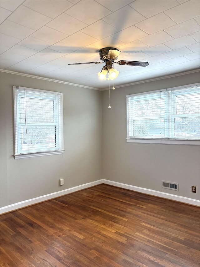 empty room featuring ornamental molding, dark hardwood / wood-style floors, and a wealth of natural light