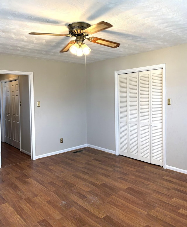 unfurnished bedroom with dark wood-type flooring, a textured ceiling, and ceiling fan