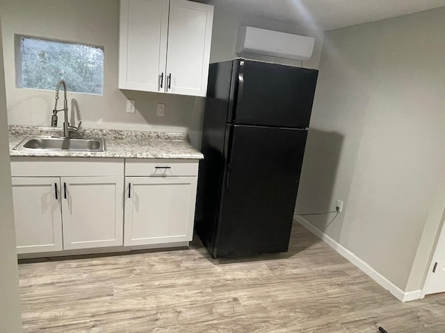 kitchen featuring black refrigerator, sink, white cabinetry, and light hardwood / wood-style floors