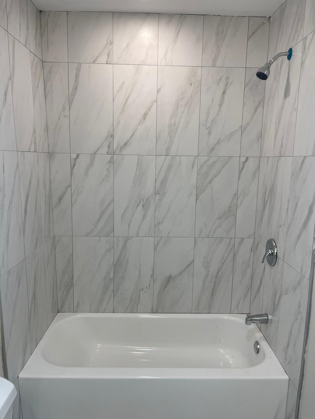 bathroom featuring tiled shower / bath combo and toilet