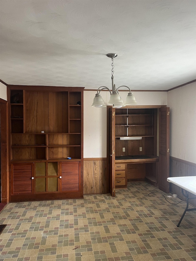 interior space with built in desk, wooden walls, and a chandelier