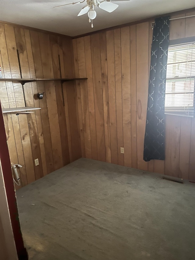 carpeted empty room featuring ceiling fan and wooden walls