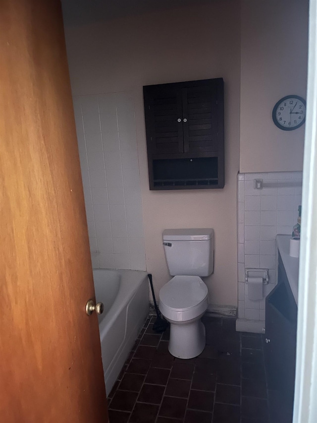 bathroom with tile patterned flooring, toilet, tile walls, and a tub to relax in