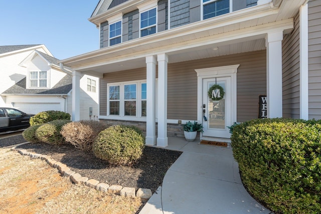 view of exterior entry featuring a garage and covered porch