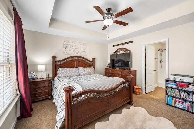 bedroom featuring a tray ceiling, light colored carpet, and ceiling fan