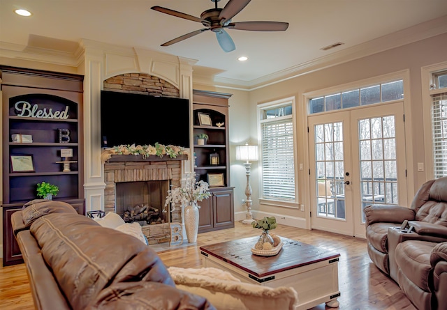 living room with french doors, ornamental molding, a fireplace, and light hardwood / wood-style floors