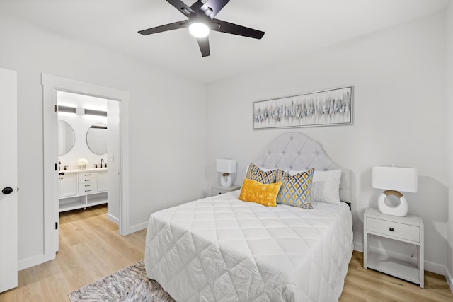 bedroom featuring ceiling fan, ensuite bathroom, sink, and light hardwood / wood-style flooring