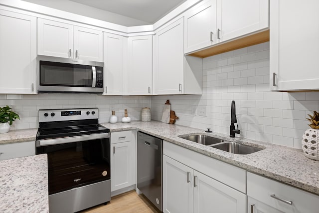 kitchen with light stone counters, sink, stainless steel appliances, and white cabinets