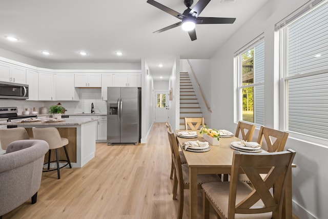 dining space featuring ceiling fan, sink, and light hardwood / wood-style flooring