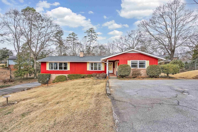 single story home with a front lawn, brick siding, driveway, and a chimney