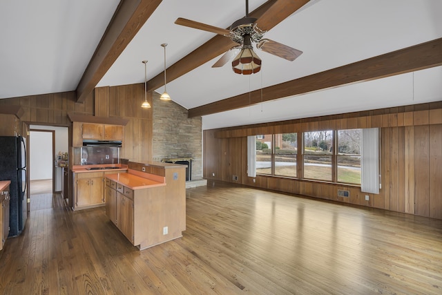 kitchen featuring wood walls, wood-type flooring, decorative light fixtures, a kitchen island, and black appliances