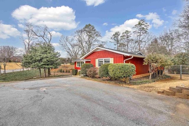 view of property exterior with aphalt driveway and fence