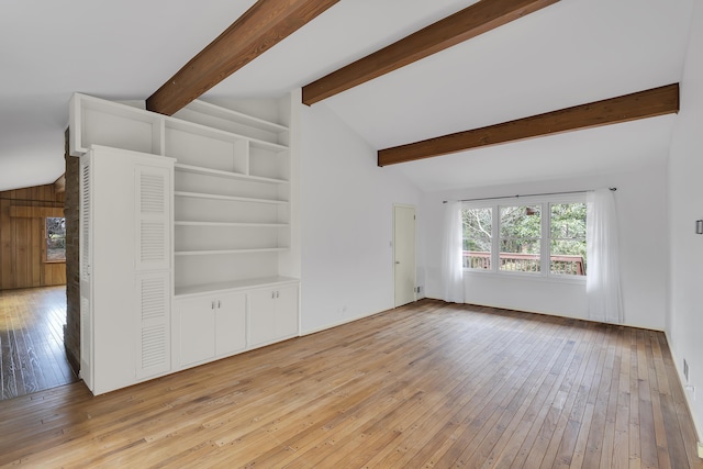 unfurnished living room featuring vaulted ceiling with beams, built in features, and light hardwood / wood-style floors