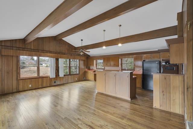 kitchen with a kitchen island, black refrigerator, wooden walls, vaulted ceiling with beams, and light hardwood / wood-style floors