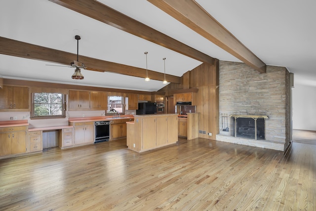 kitchen with a fireplace, decorative light fixtures, lofted ceiling with beams, sink, and black appliances