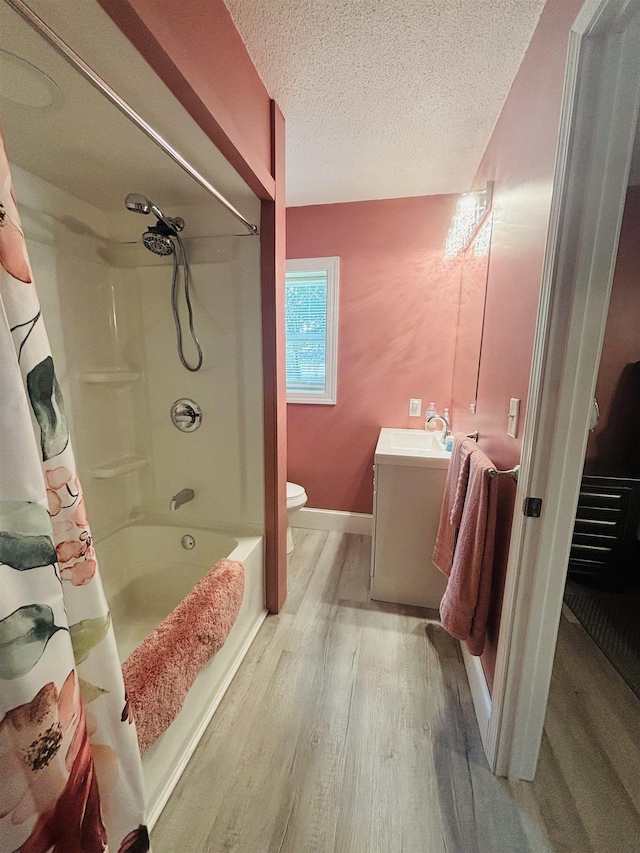 full bathroom featuring hardwood / wood-style floors, vanity, toilet, shower / bathtub combination with curtain, and a textured ceiling