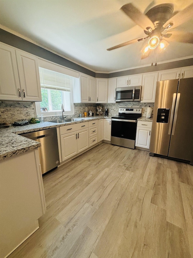 kitchen featuring light stone counters, stainless steel appliances, sink, and white cabinets